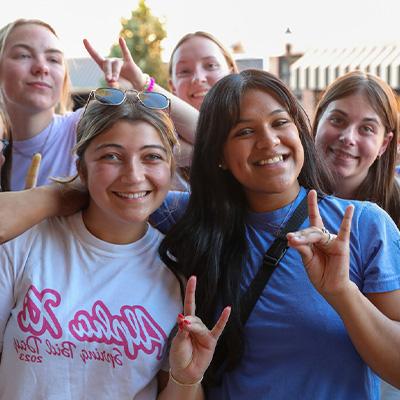 students pose for a photo outdoors, throwing their lopes